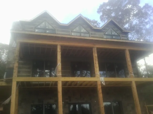 Dormers and porch framing on a large log home under construction — Roof Coating work by our crew in Winslow